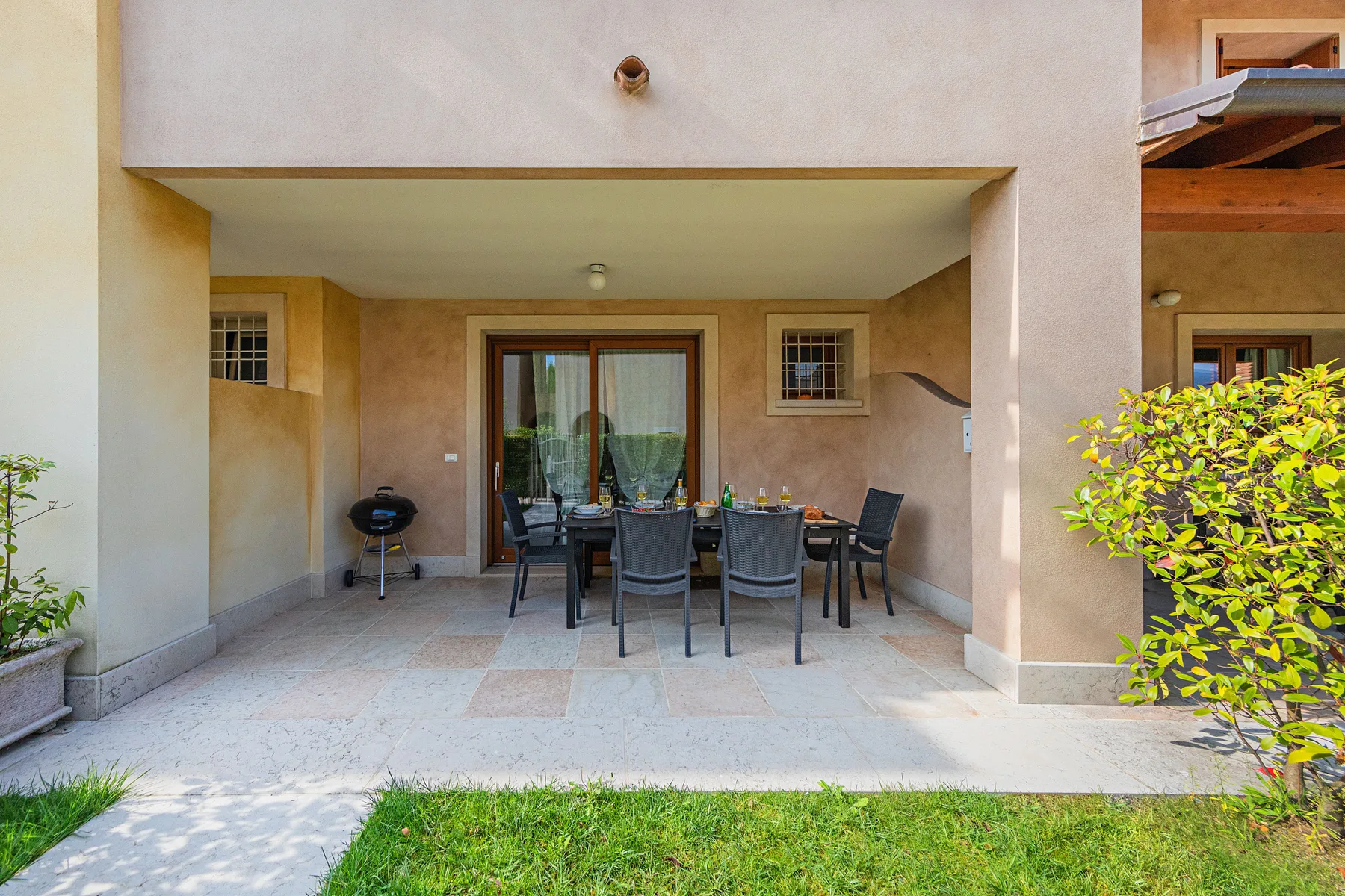 A covered patio with outdoor seating and a glass door.
