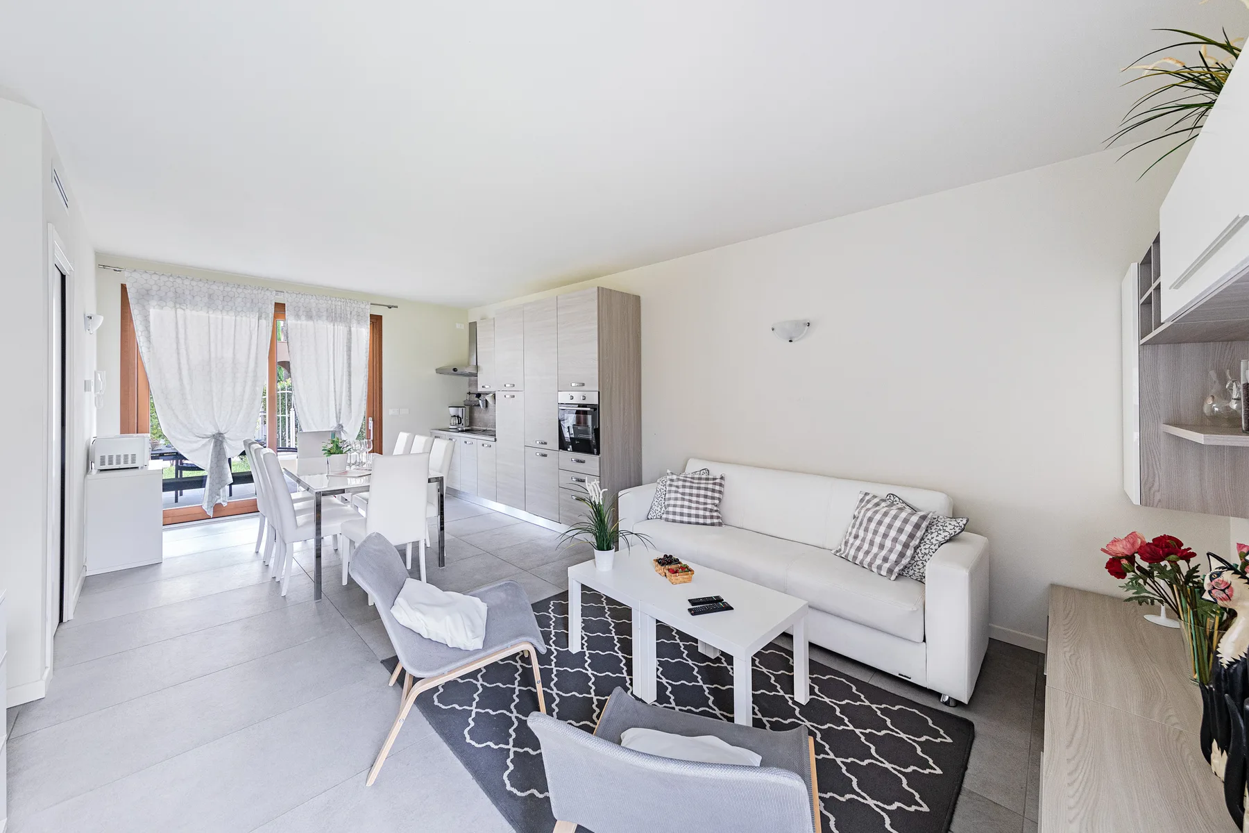 A bright living room with seating and an open kitchen-dining area.