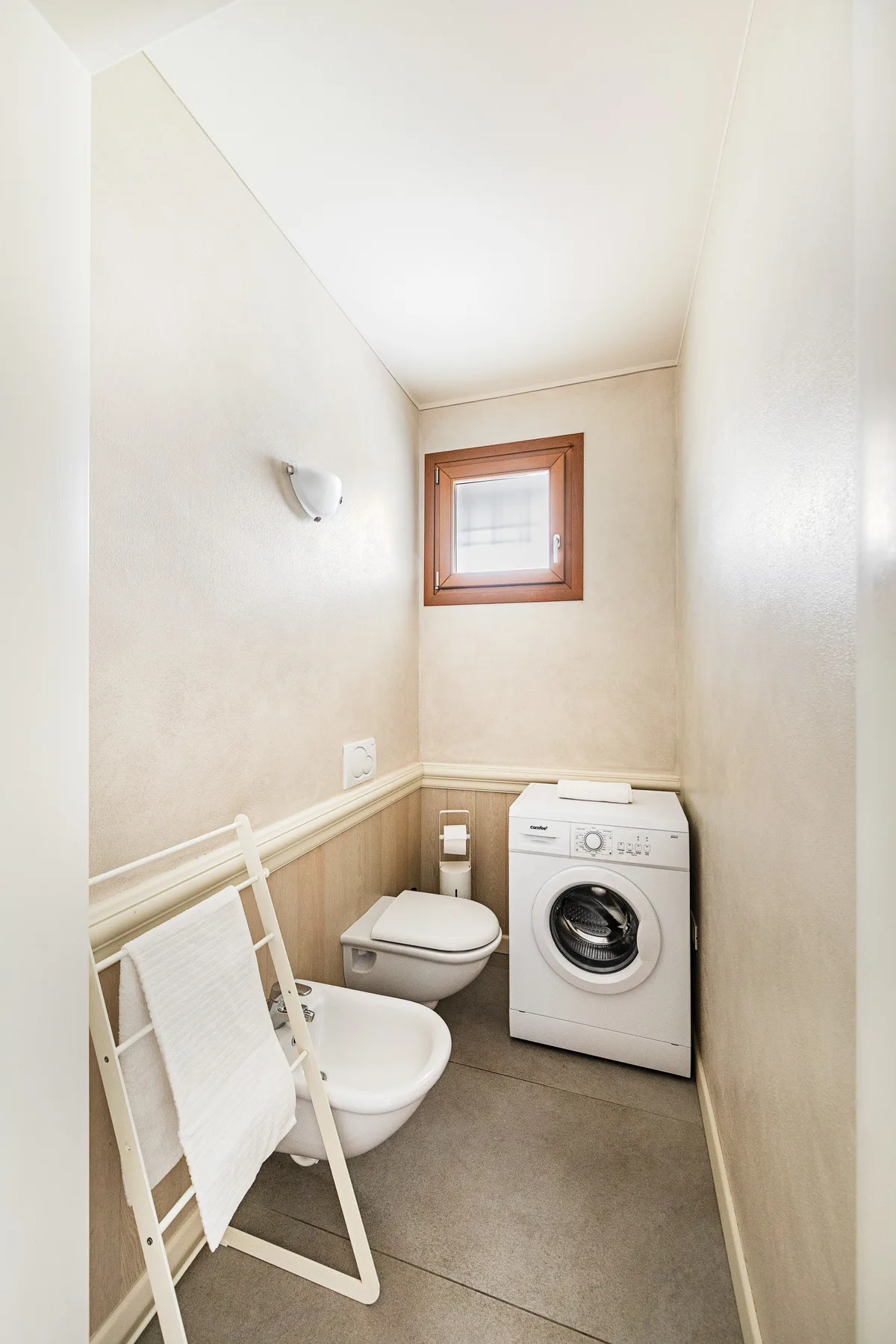 A compact bathroom with a toilet, sink, and washing machine.