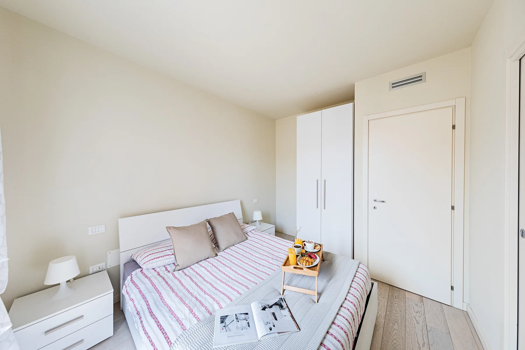 A bedroom with a bed covered in striped bedding and a bedside cabinet.