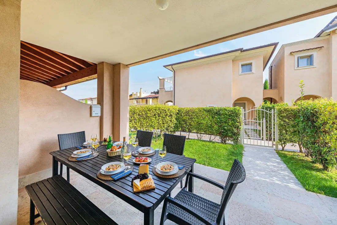 An outdoor dining area with a table and seating overlooks a green garden.