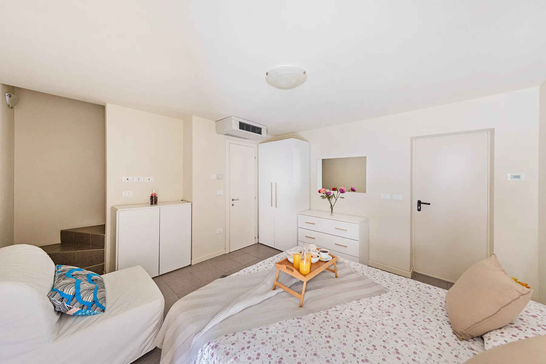 A bedroom with a bed, a white wardrobe, and a small table.