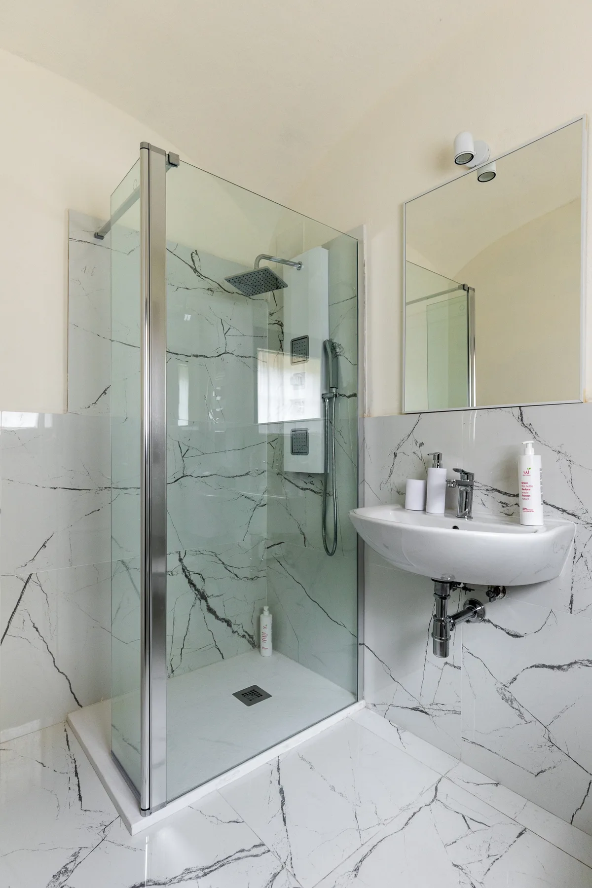 A bathroom with a glass shower and a wall-mounted sink.