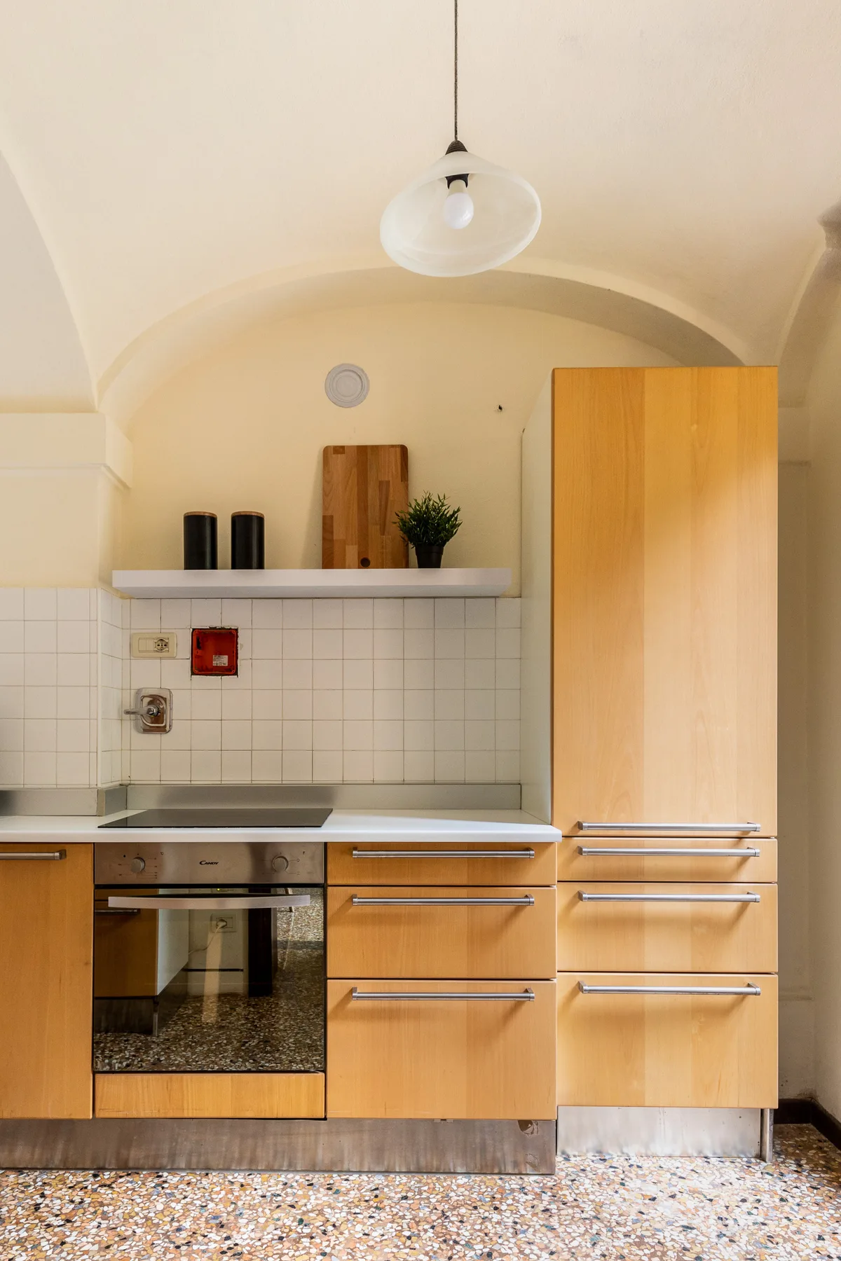 A kitchen with wooden cabinets and a built-in oven beneath a tiled backsplash.