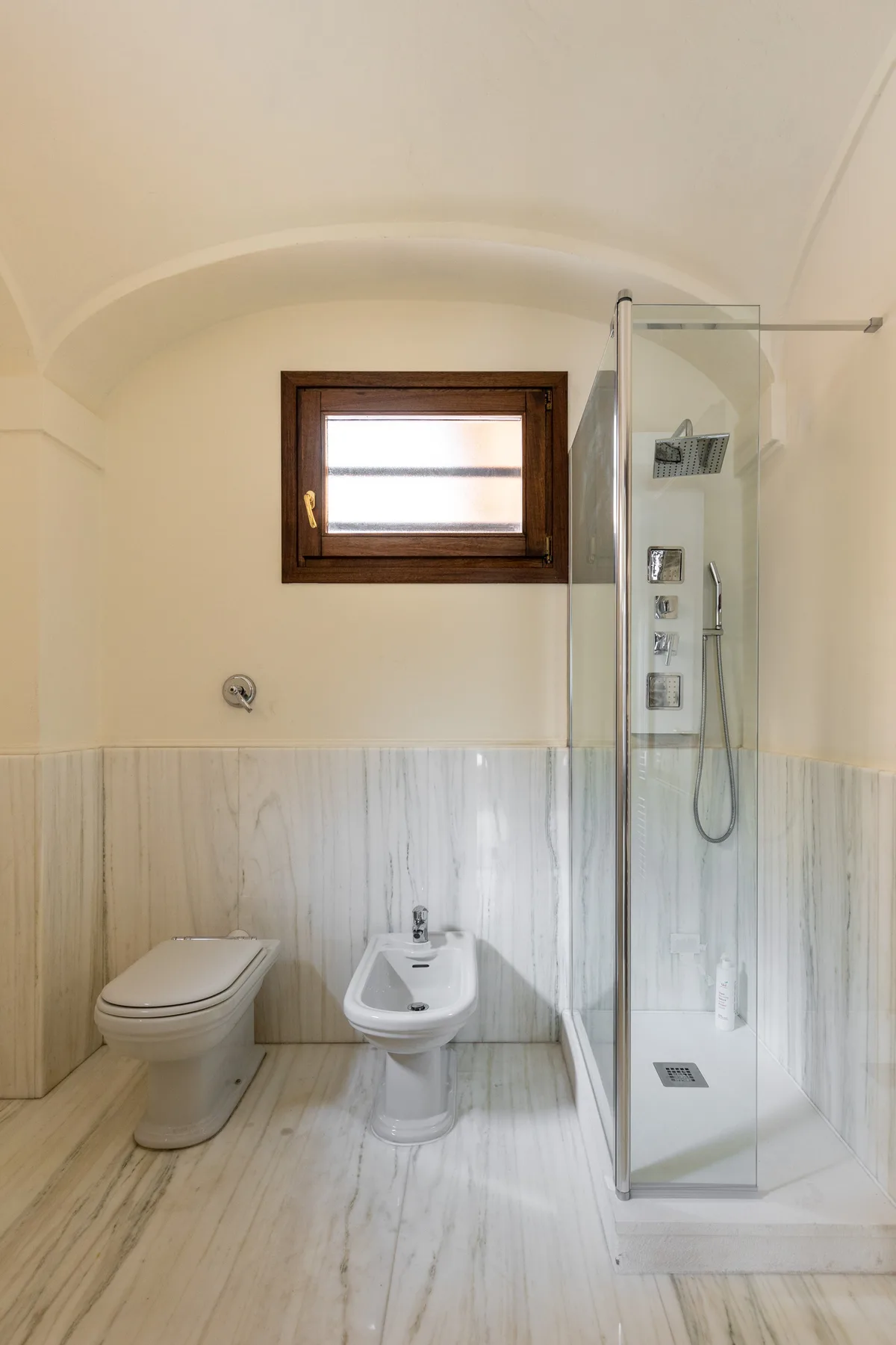 A bathroom with a toilet, bidet, and glass shower.