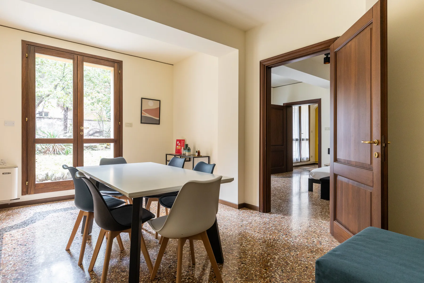 A dining area with a table and chairs beside tall windows.