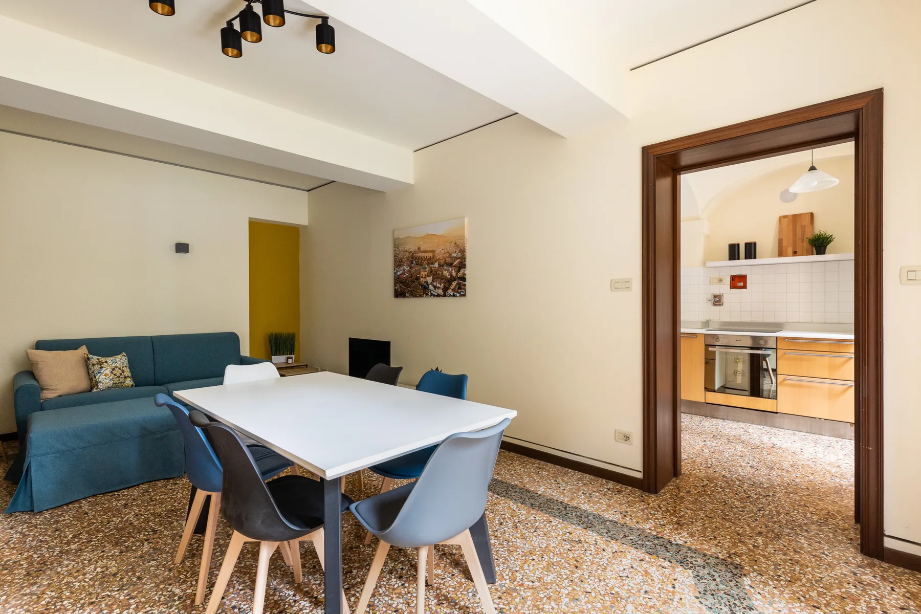 A dining area opens into a kitchen, with a table and seating in the foreground.