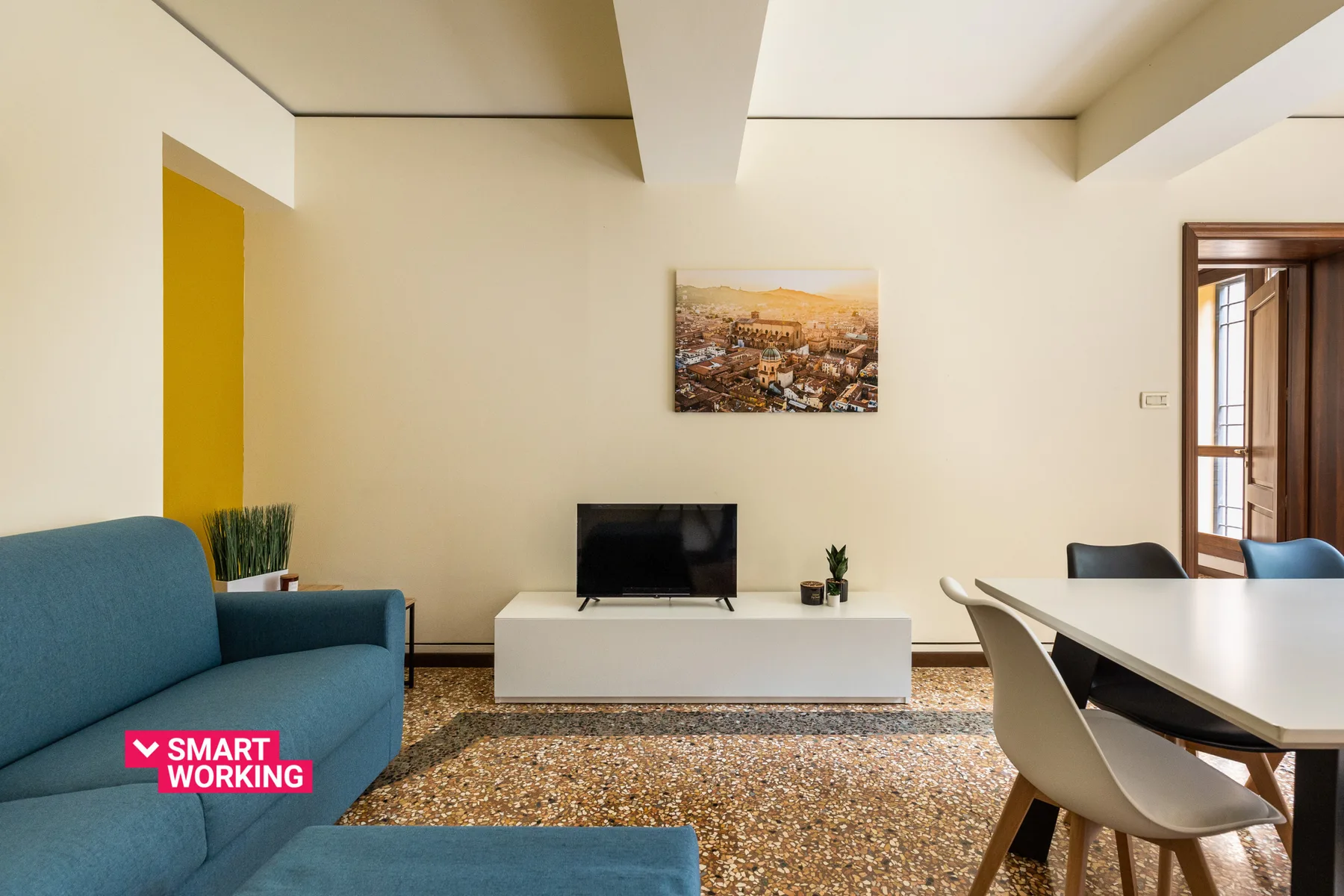 A living room with blue seating, a television, and a dining table.