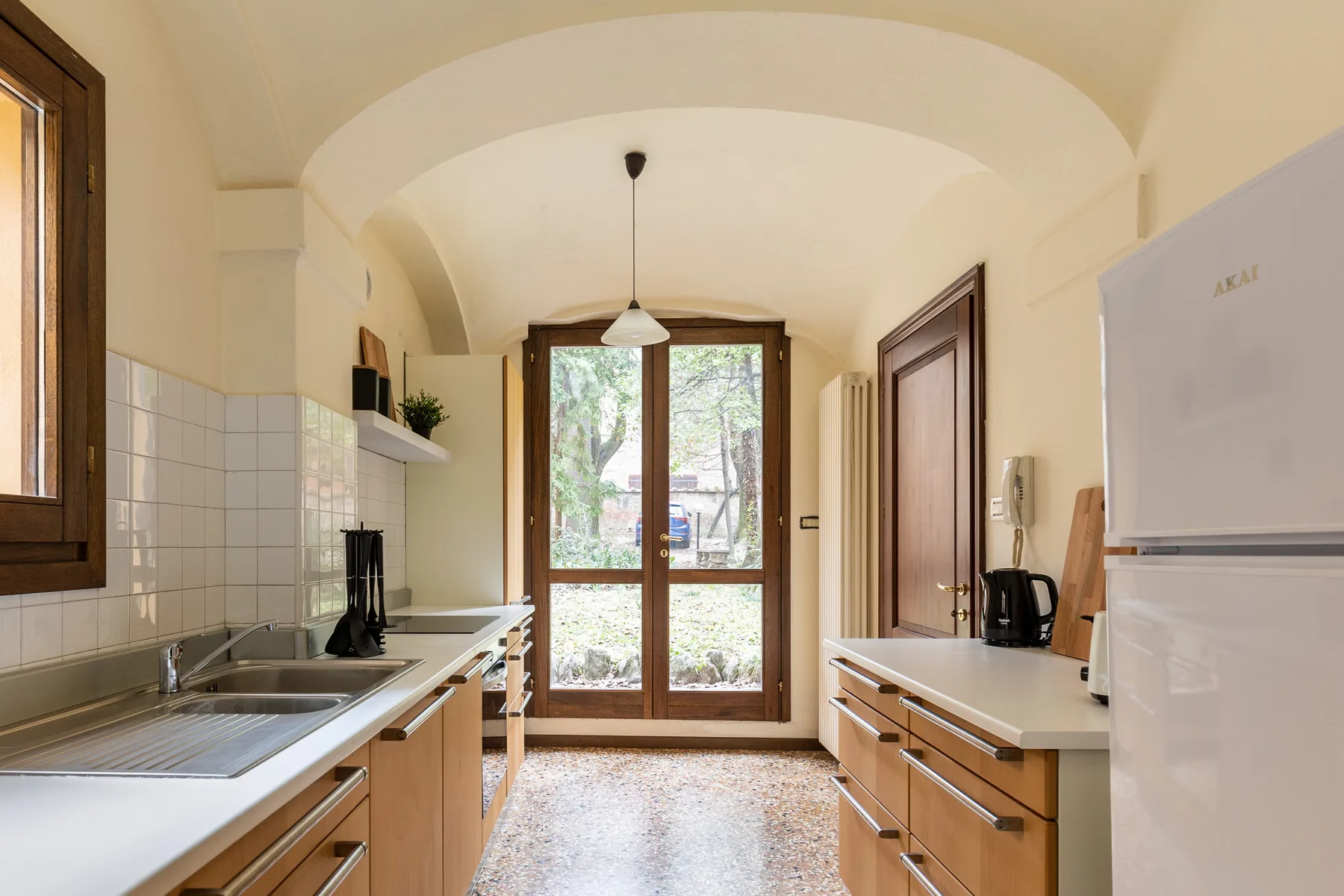 A galley kitchen with wooden cabinetry and a glass door at the far end.