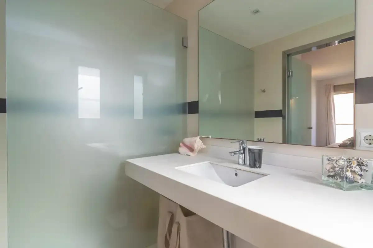 A bathroom vanity with a broad white countertop and wall mirror.