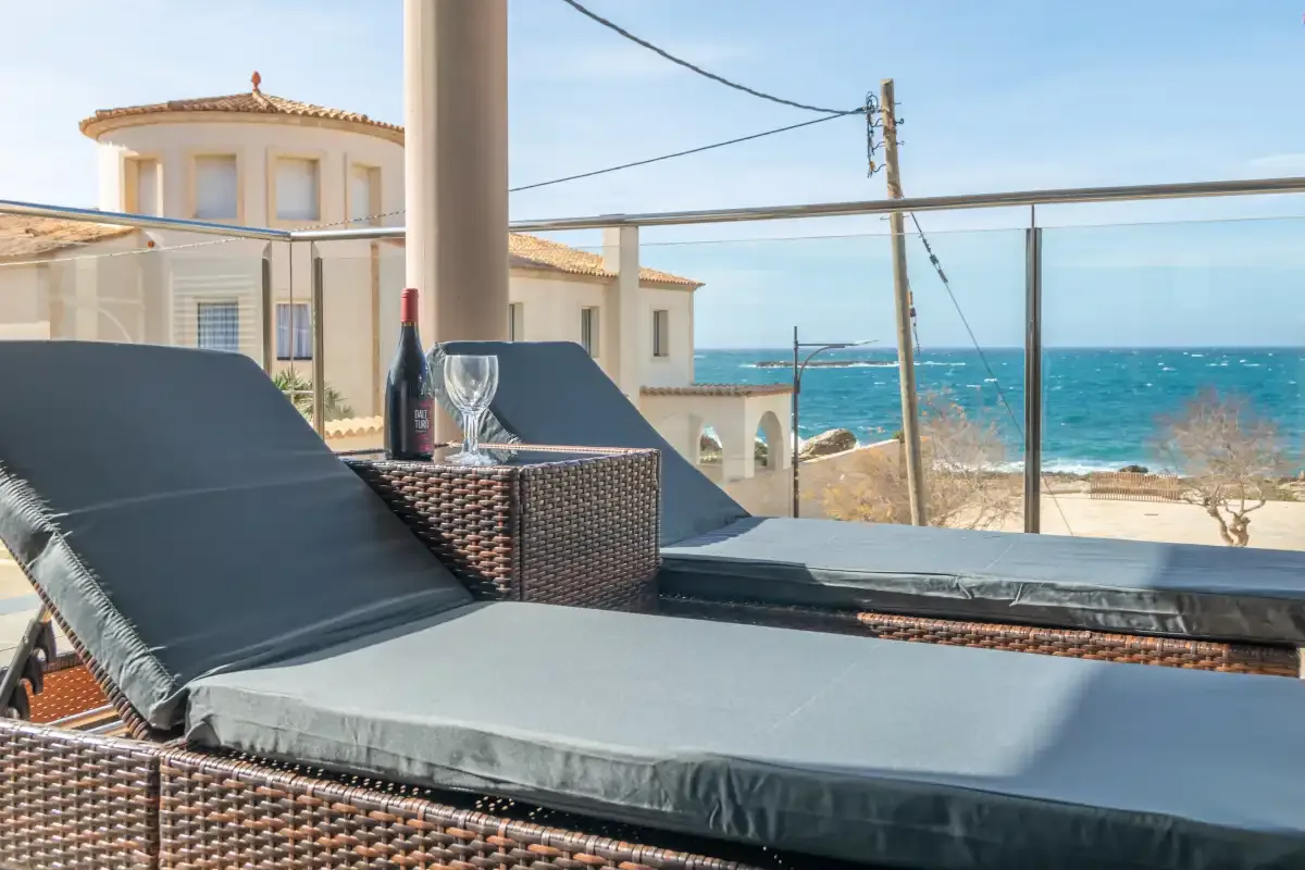Outdoor lounge seating overlooks the sea from a terrace.