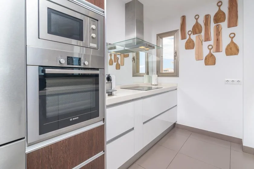 A modern kitchen with built-in appliances, white cabinets, and wooden wall decorations.