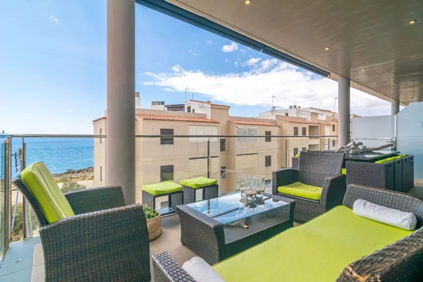 A furnished seaside terrace with outdoor seating and a glass coffee table.