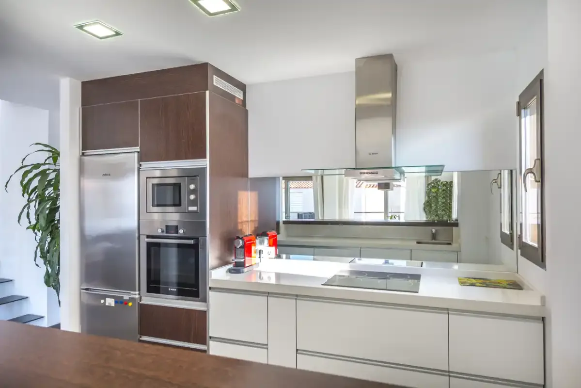 Modern kitchen with white cabinetry, stainless steel appliances, and a cooktop.