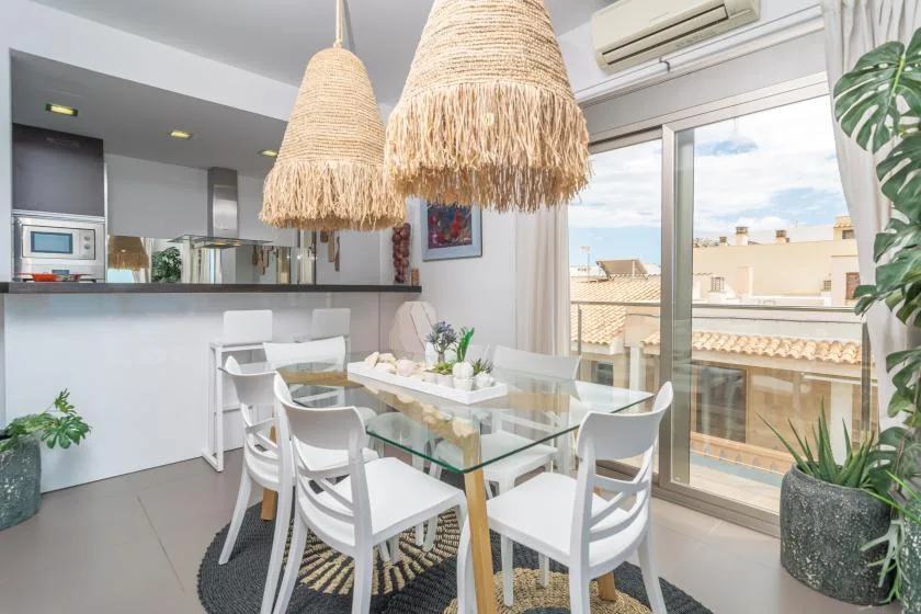 A bright dining area with a glass table beside large windows.