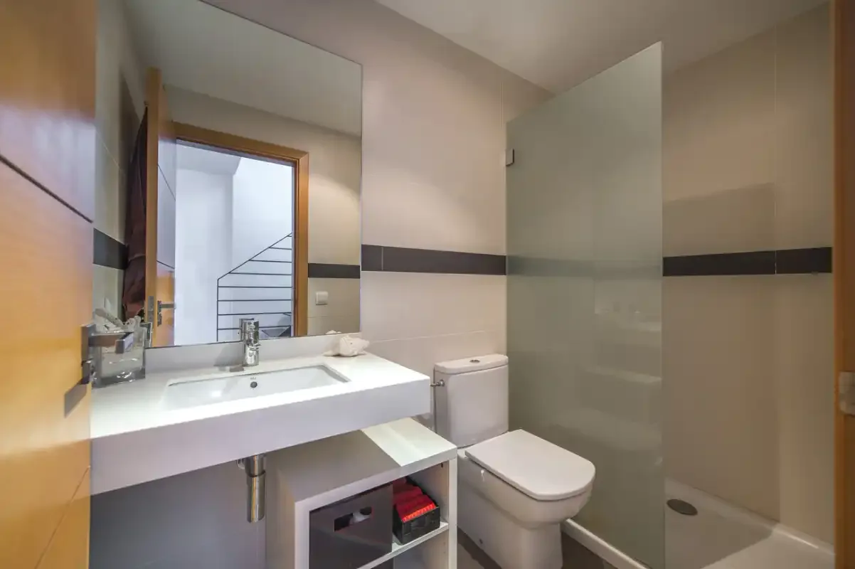 A bathroom with a sink, toilet, and glass shower screen.