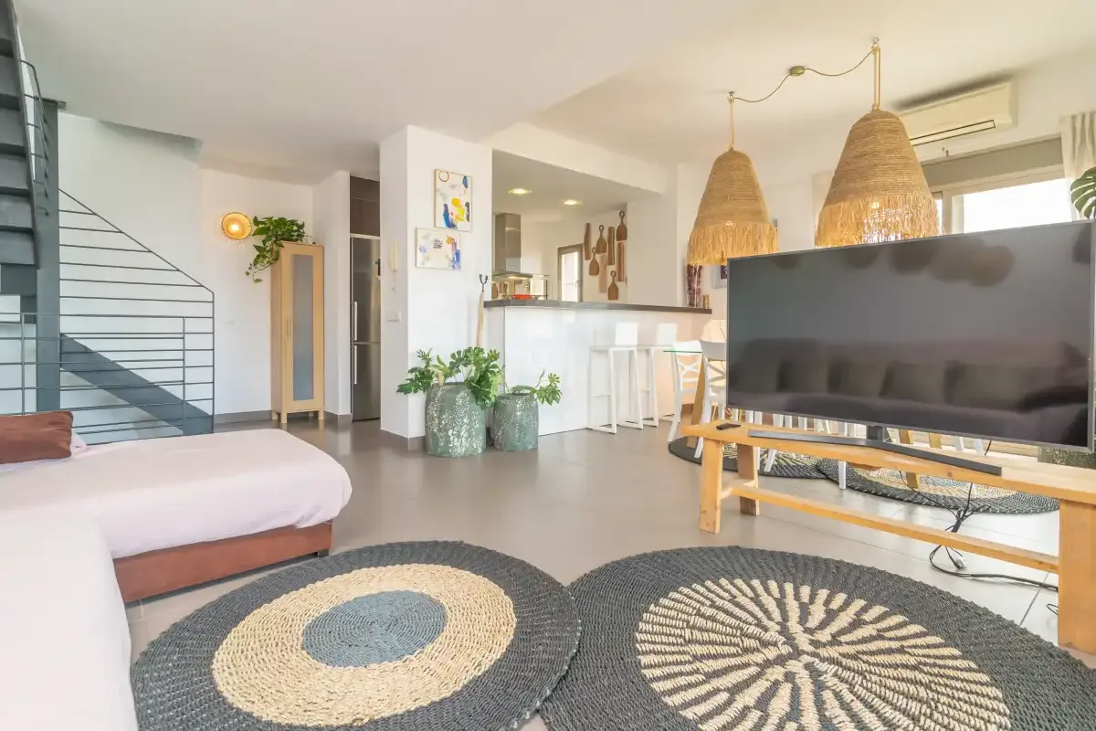 A bright living area with a television, seating, and a kitchen counter.