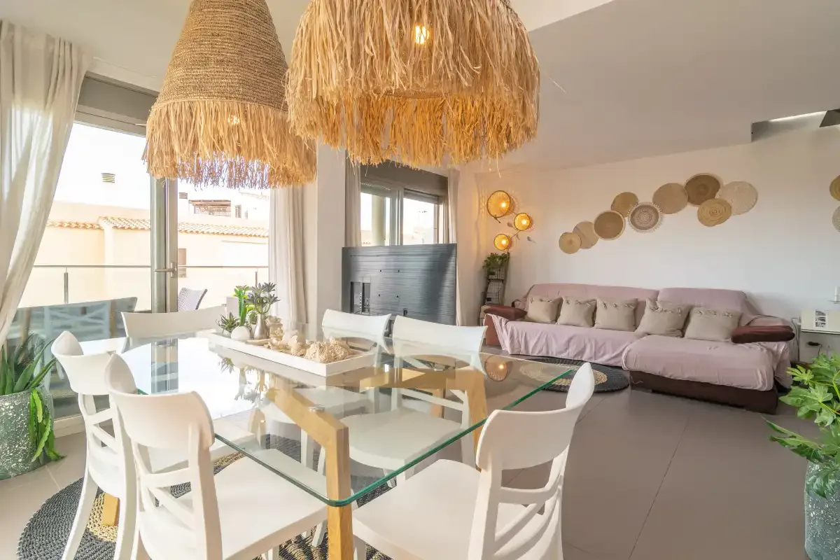 A bright open-plan living and dining area with a glass dining table and seating.