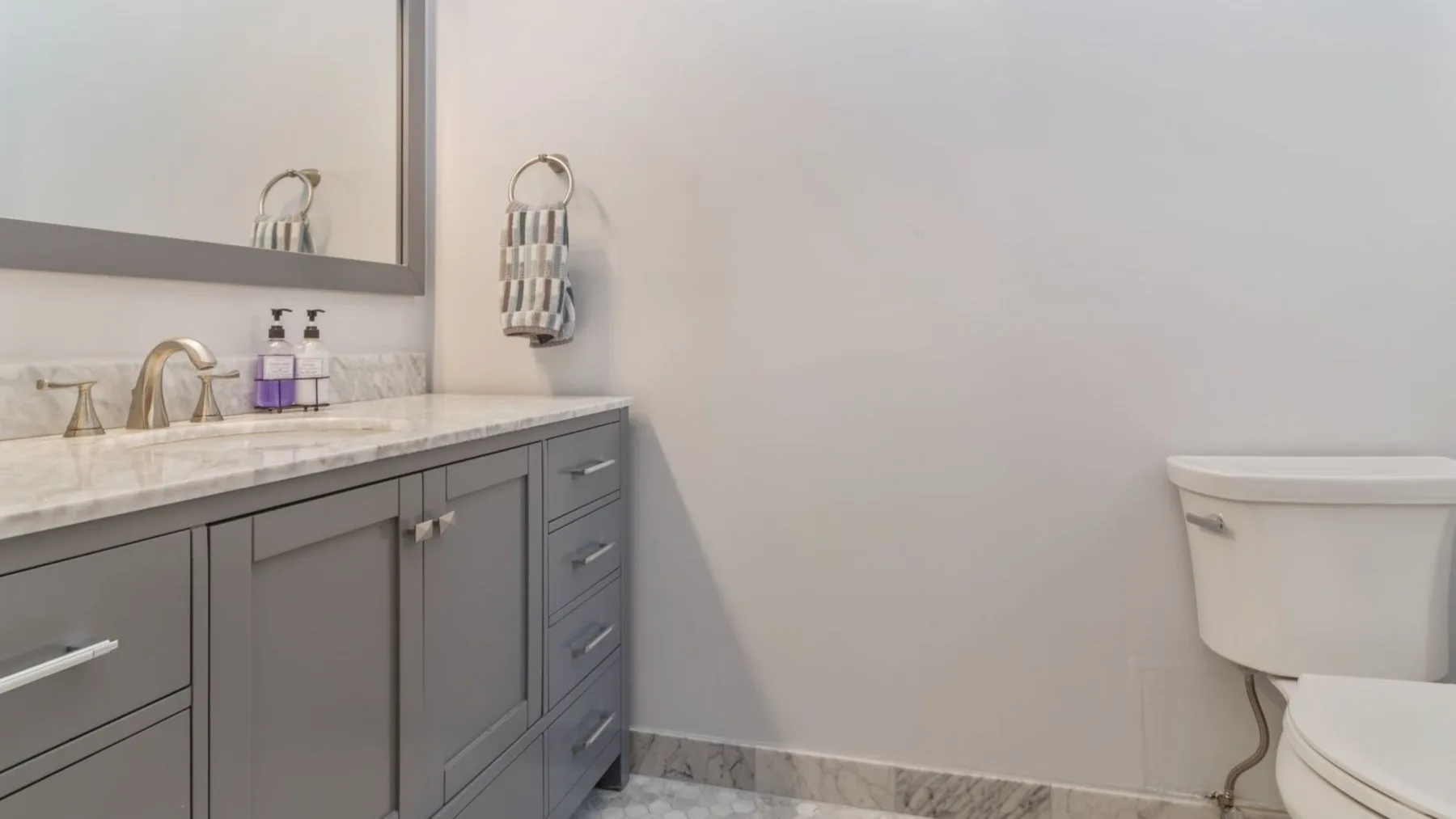 A bathroom vanity with a sink and a toilet against a light wall.