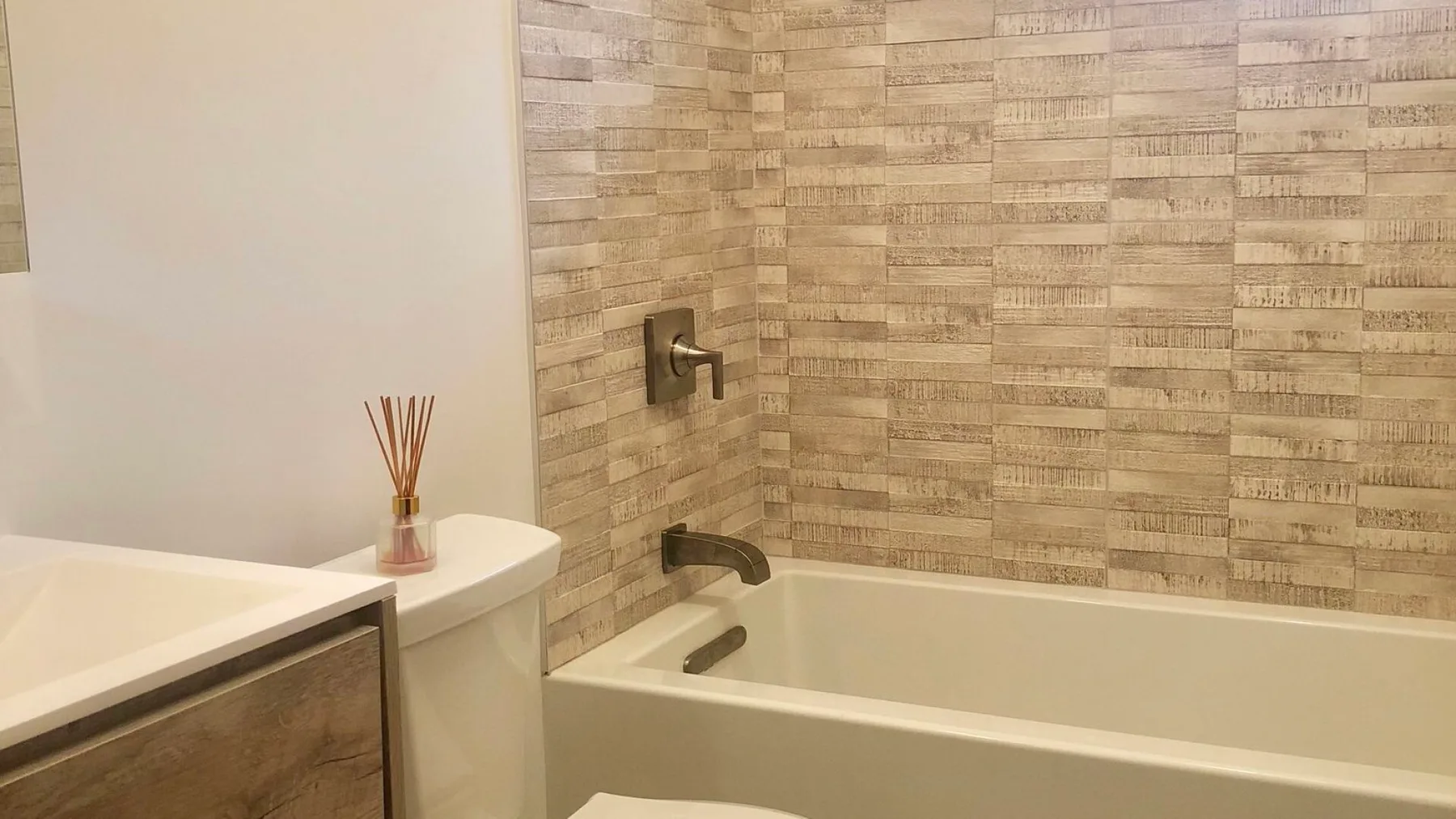 A bathroom with a bathtub, tiled walls, and a vanity.