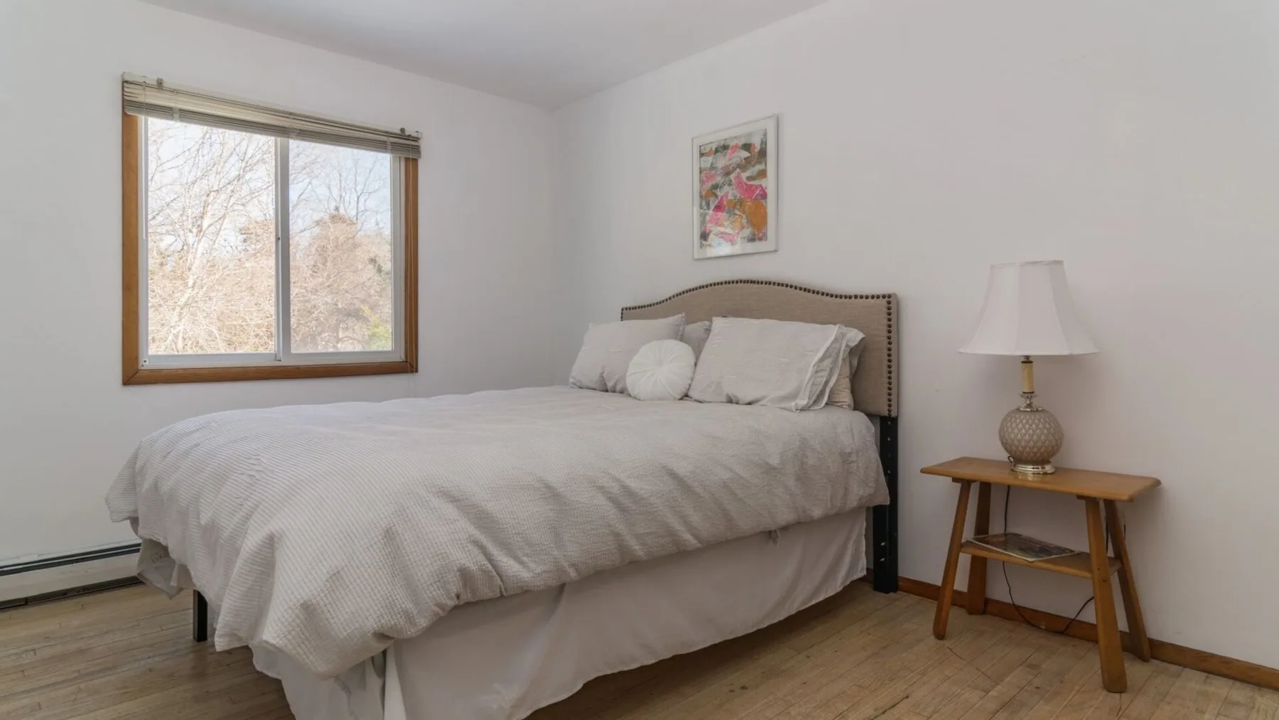 A bright bedroom with a neatly made bed and a window.