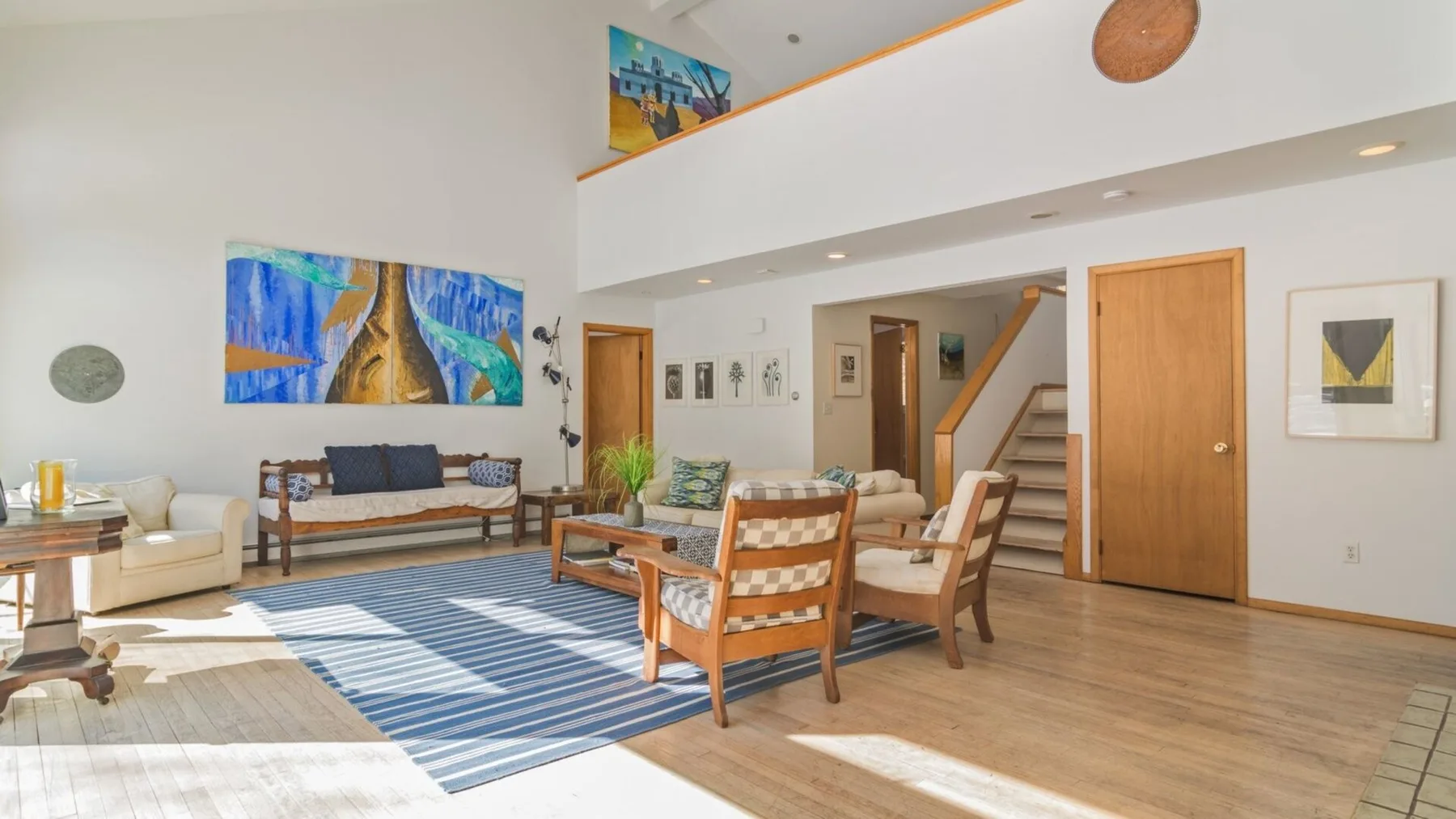 A bright living room with seating arranged around a blue striped rug.