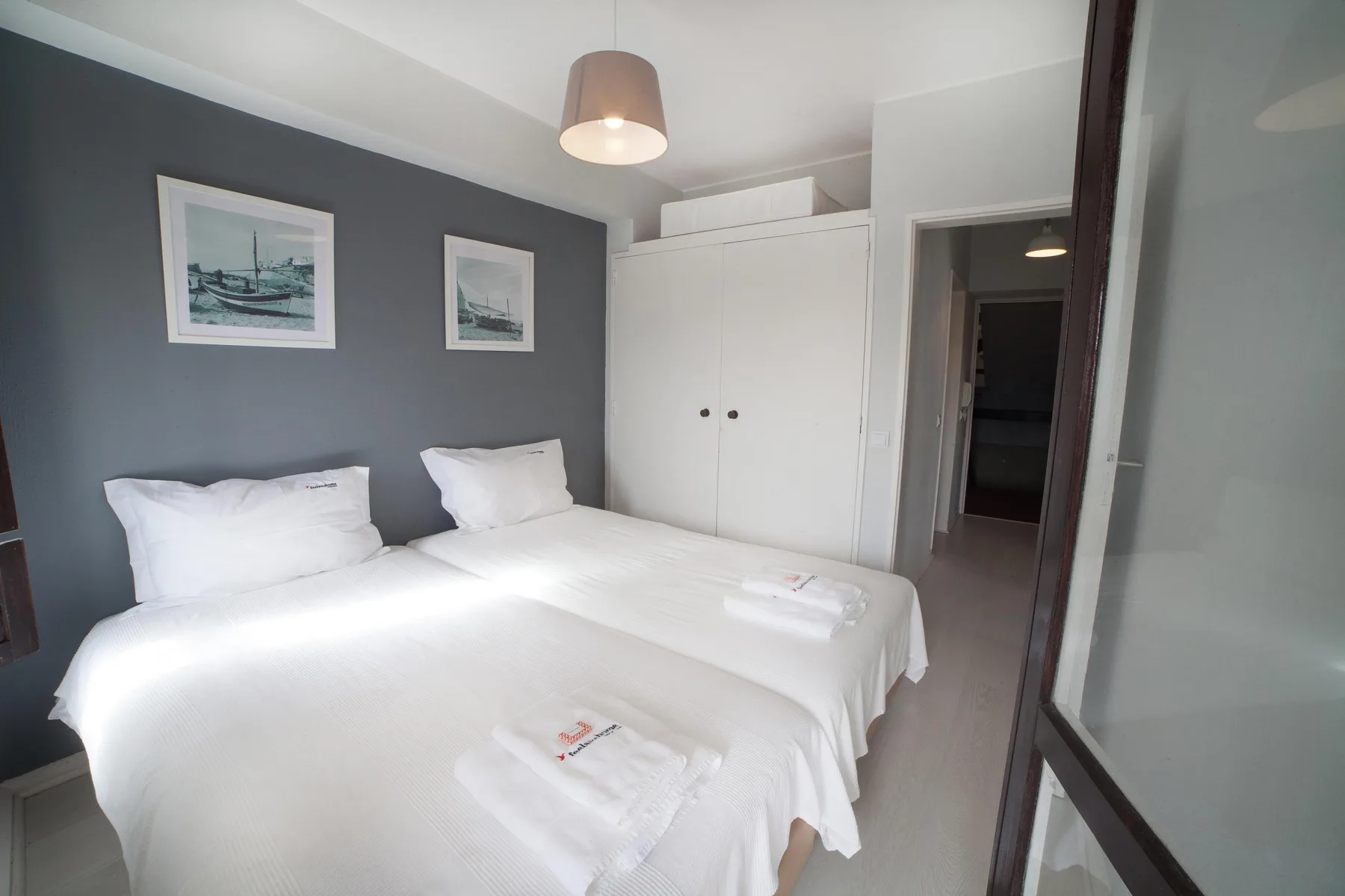 A bedroom with a double bed, white bedding, and framed pictures on the wall.