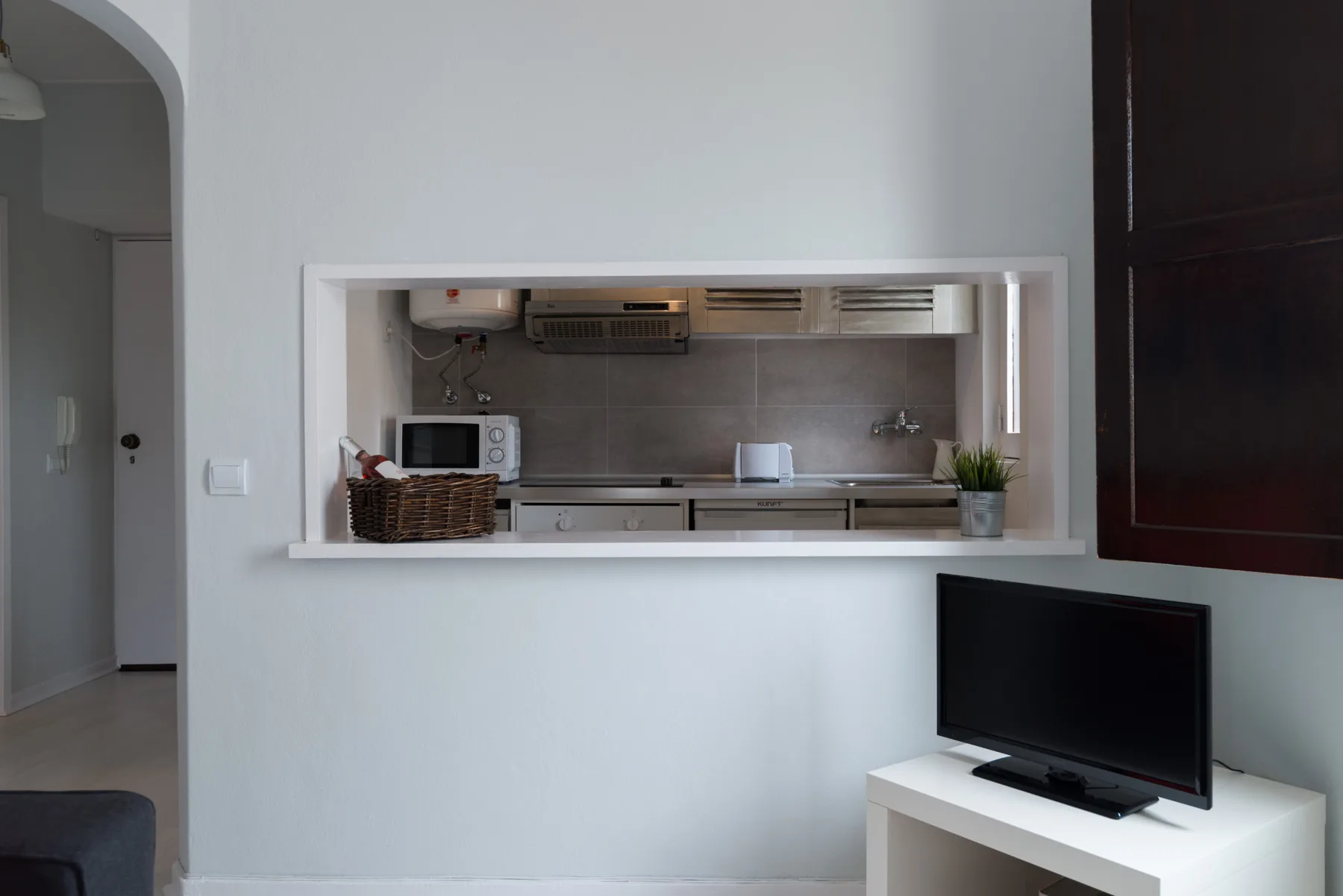 A kitchen is visible through a pass-through, with a television in the foreground.