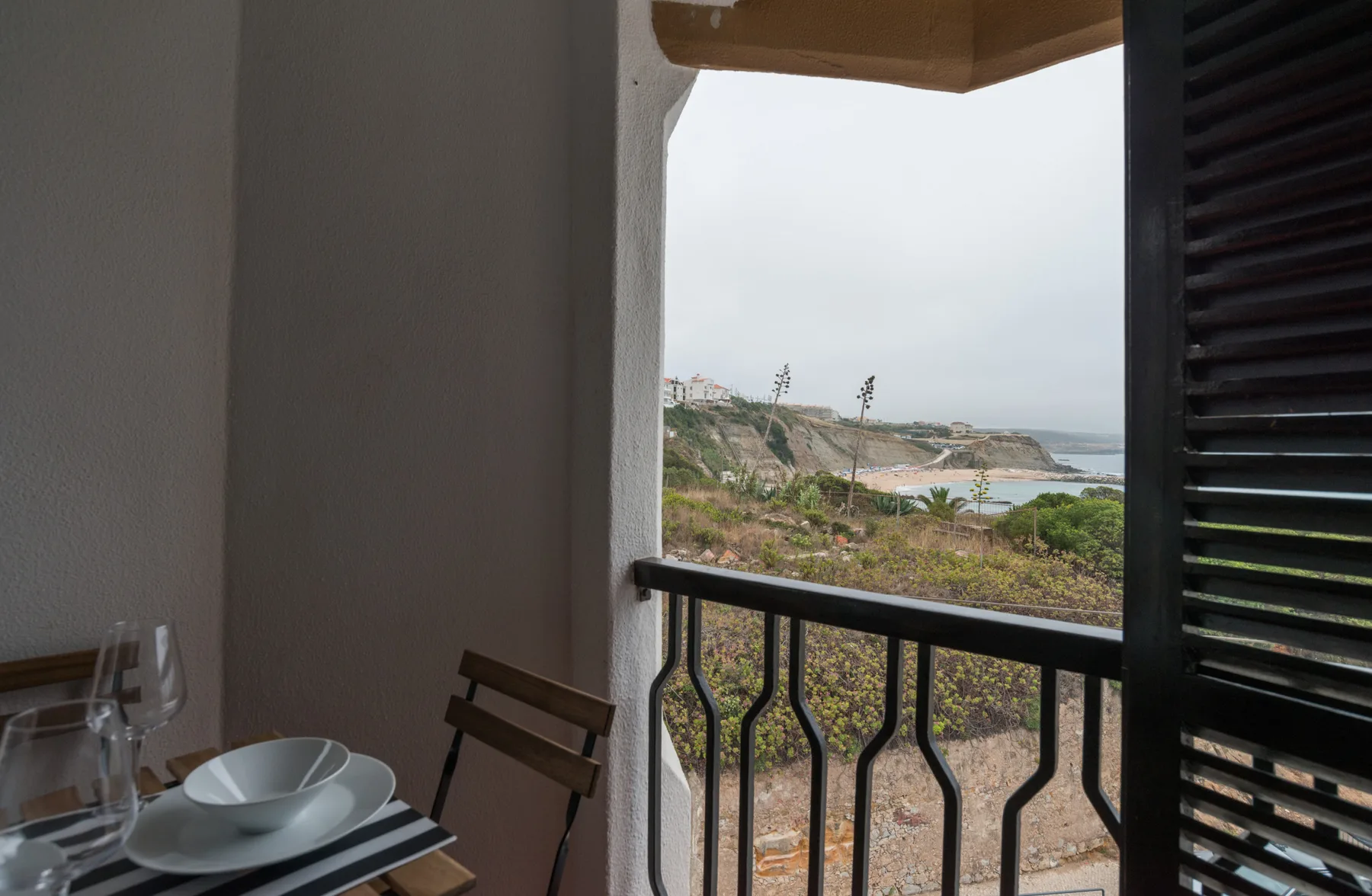 A dining area opens onto a balcony overlooking the coastline.