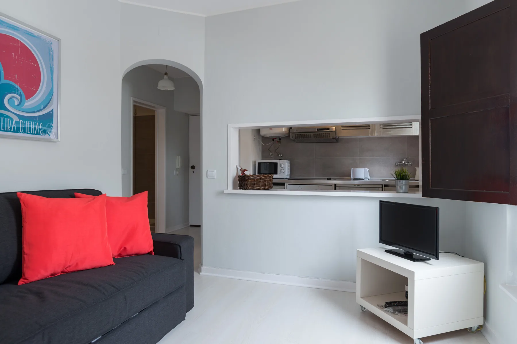 A living room with dark seating and a pass-through to the kitchen.