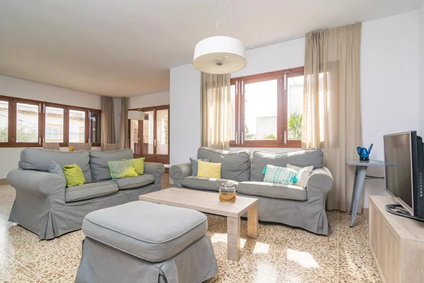 A living room with gray seating, a coffee table, and windows.