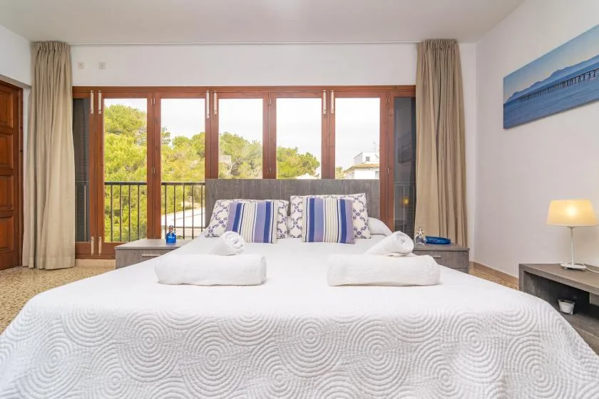 A bedroom with a large bed facing glass doors and a balcony.