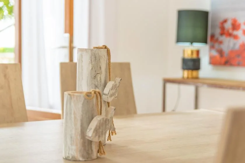 A dining area with a pale table and a small carved wooden ornament in the foreground.