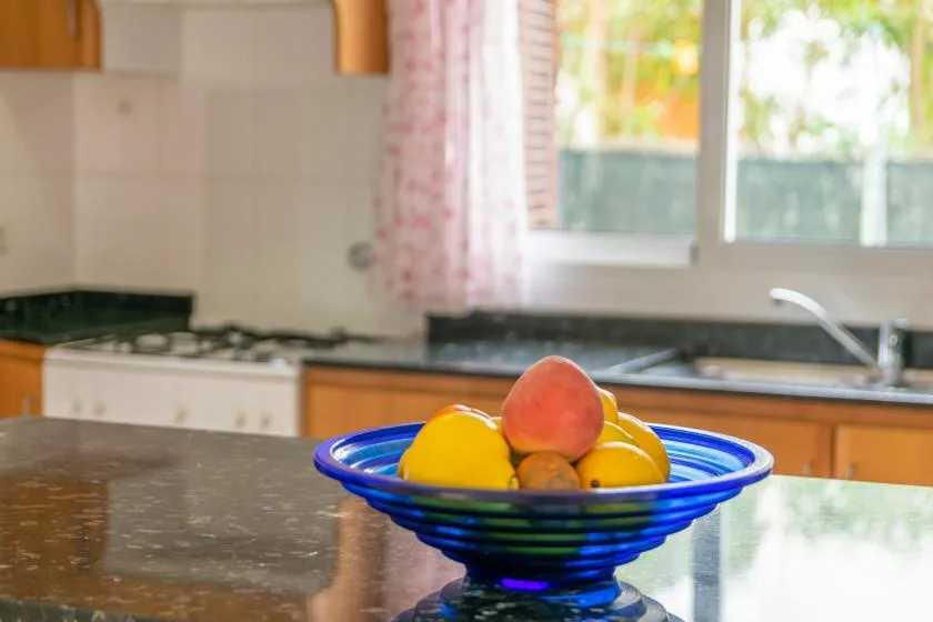 A kitchen counter with a blue bowl of fruit in the foreground.