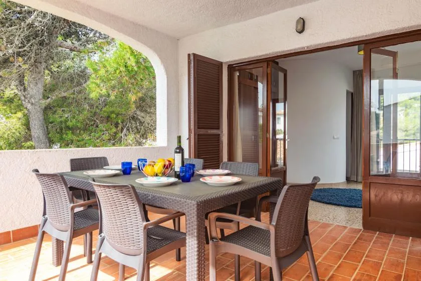 A covered patio dining area with a table and chairs beside an open doorway.
