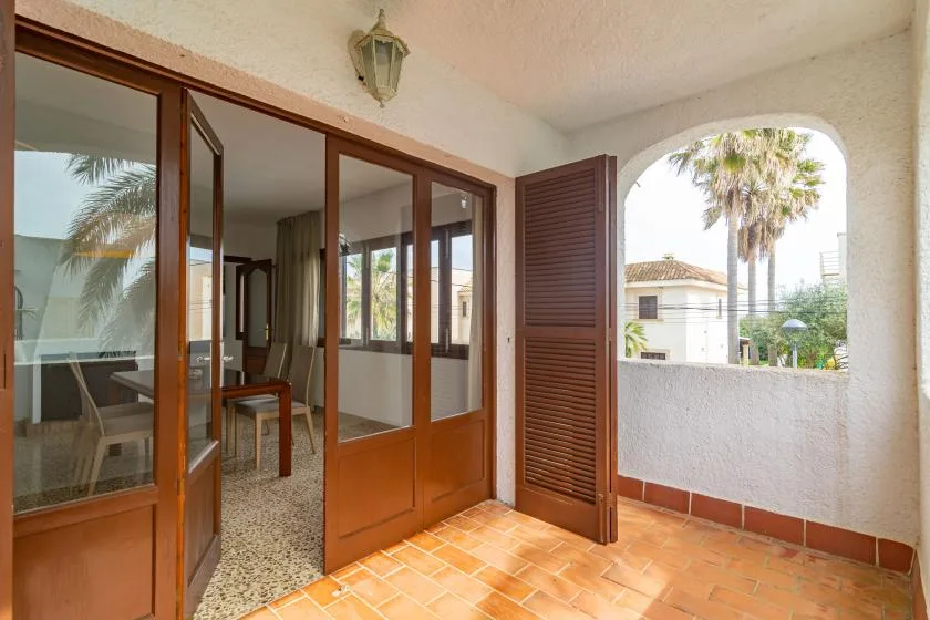 A tiled patio beside glass doors, with a view of a palm tree through an arched opening.