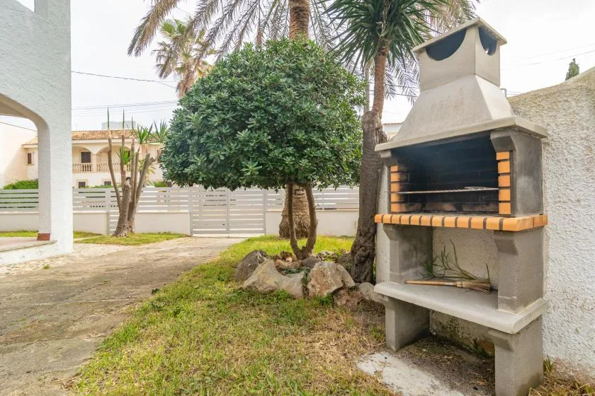 An outdoor patio with a built-in barbecue beside a small landscaped garden.