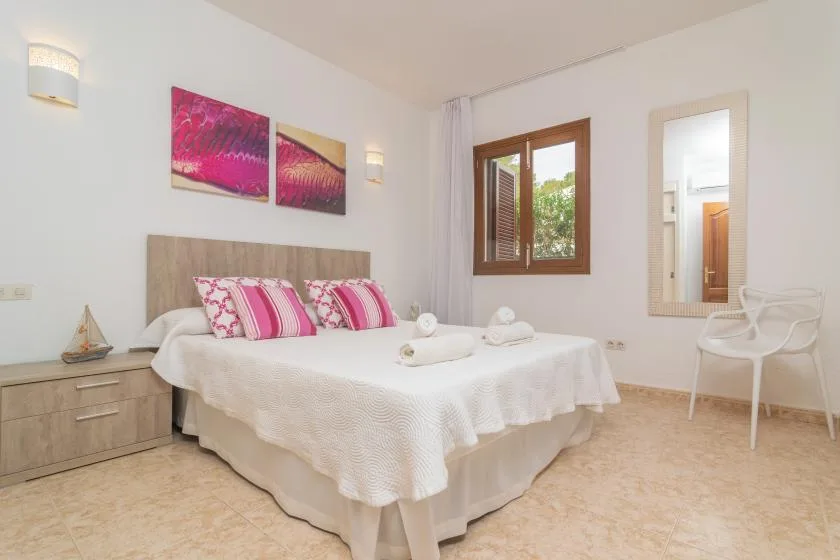 A bright bedroom with a neatly made bed and colorful artwork above it.