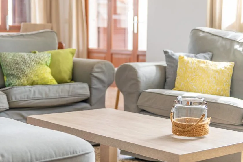 A living room with gray seating, colorful cushions, and a low table.