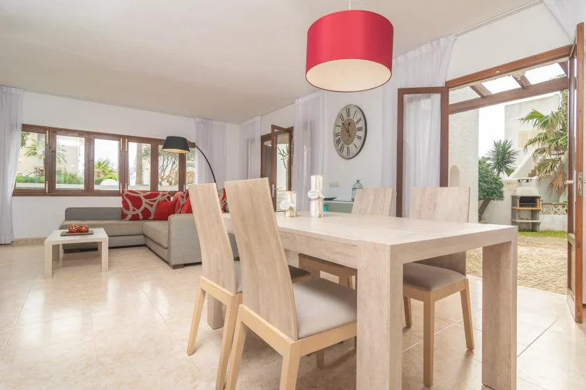 A bright open-plan dining and living area with a wooden table and seating.