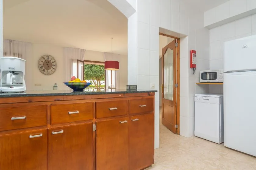 A bright kitchen with wooden cabinets, a fruit bowl, and appliances.
