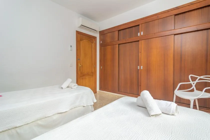 A bedroom with two beds and built-in wooden wardrobes.