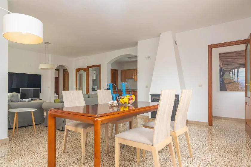 A dining area with a wooden table and light-colored chairs beside the living room.