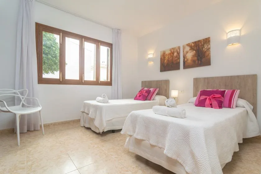 A bright bedroom with two beds dressed in white linens and pink accents.