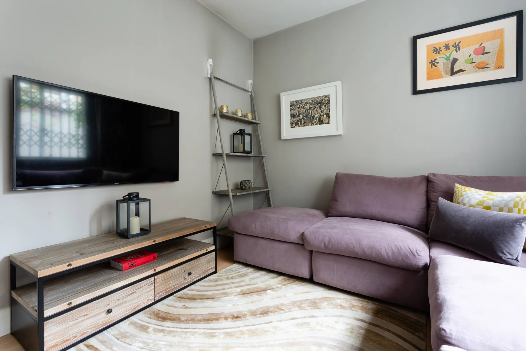 A living room with a television, seating, and framed wall art.