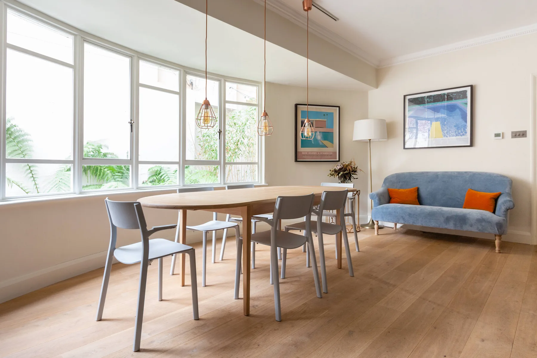 A bright dining and sitting area with a wooden table and blue seating.