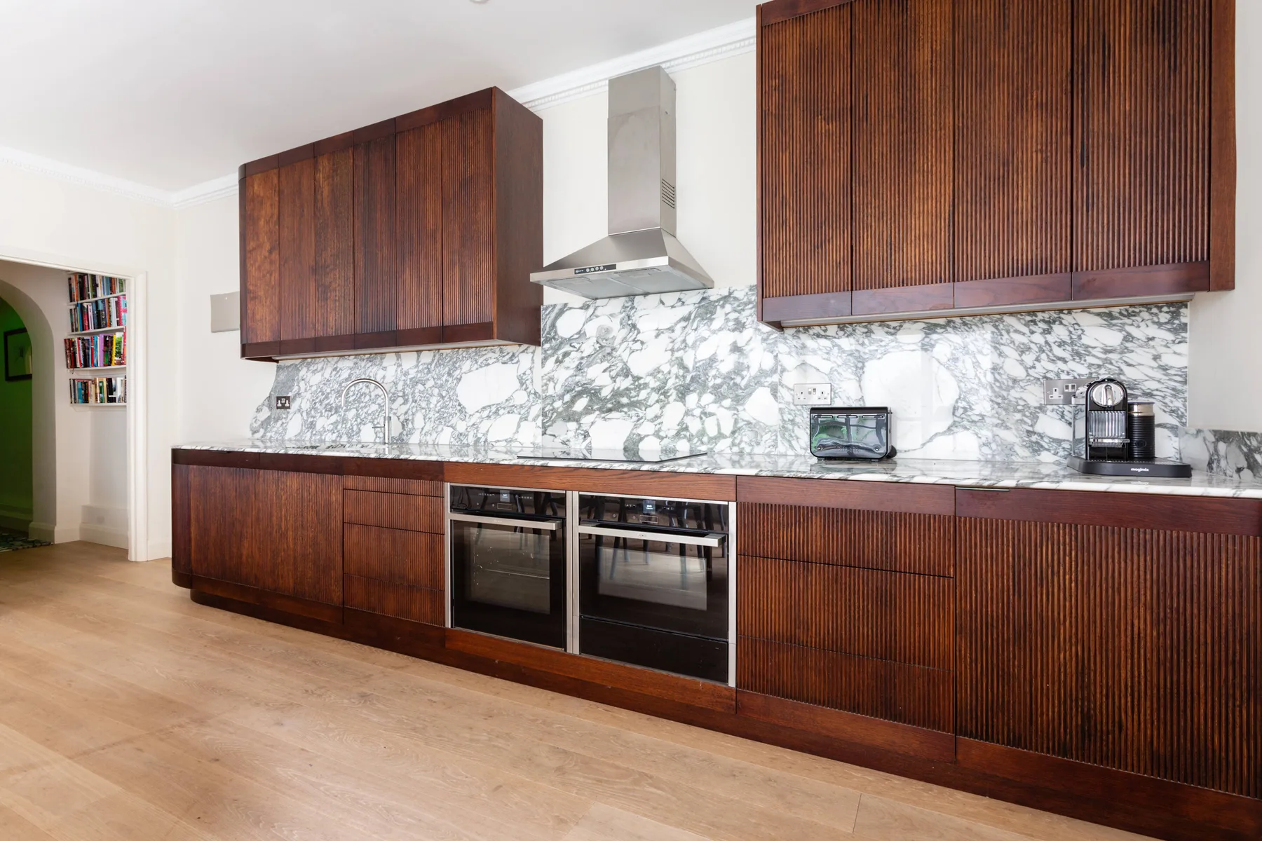 A modern kitchen with dark wood cabinetry and a marble-patterned backsplash.