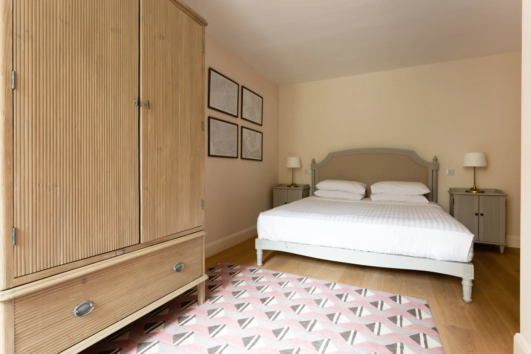 A bedroom with a double bed, bedside tables, and a patterned rug.