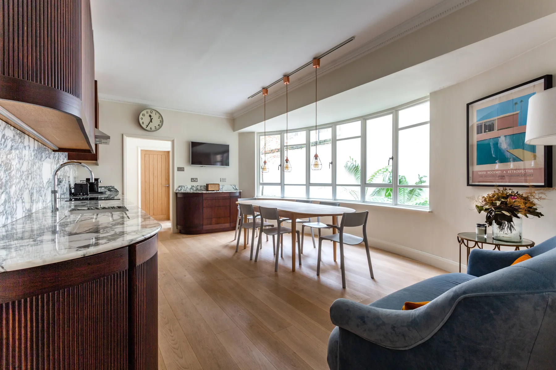 A bright open-plan kitchen and dining area with large windows and a dining table.