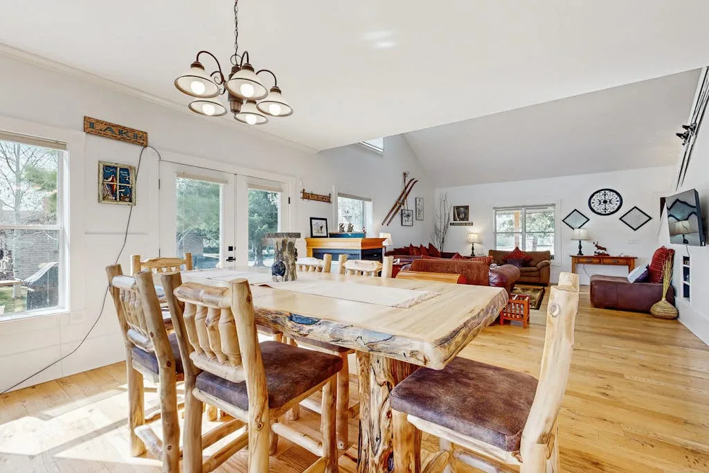Comedor con una gran mesa de madera y asientos, junto a una zona de estar.
